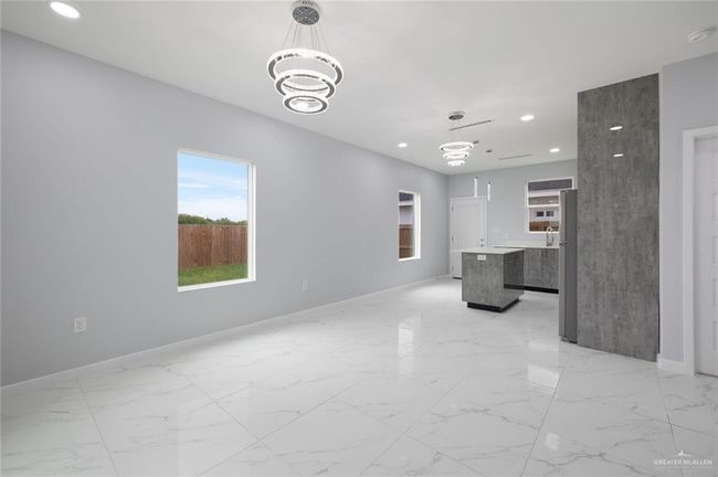 Unfurnished living room with recessed lighting, a chandelier, baseboards, and light marble finish flooring | Image 17