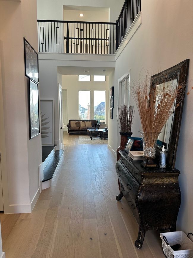 Hall featuring a high ceiling, light wood-style flooring, and baseboards | Image 7
