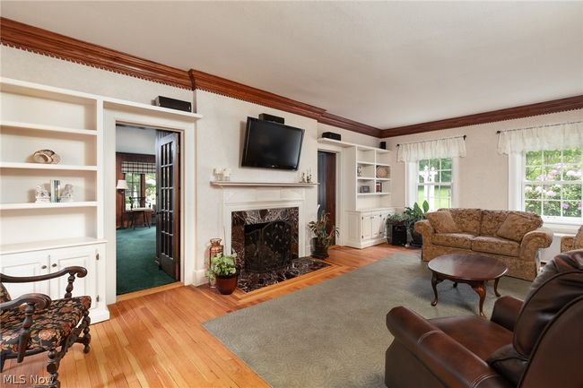 Living room featuring built in shelves, a high end fireplace, light hardwood / wood-style flooring, and ornamental molding | Image 17