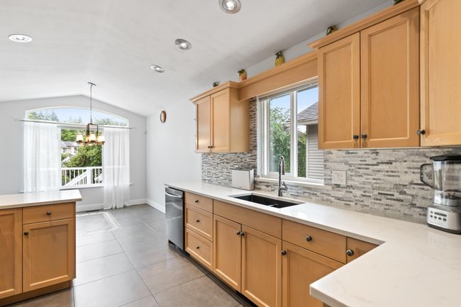 Kitchen with a sink, stainless steel dishwasher, lofted ceiling, light countertops, and backsplash | Image 6