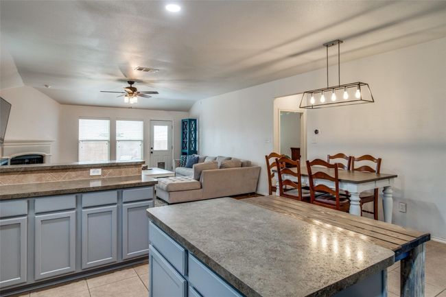 Kitchen featuring a ceiling fan, light tile patterned floors, open floor plan, gray cabinetry, and decorative light fixtures | Image 10