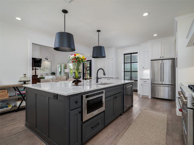 Kitchen with stainless steel appliances, white cabinets, crown molding, a kitchen island with sink, and gray cabinets | Image 13