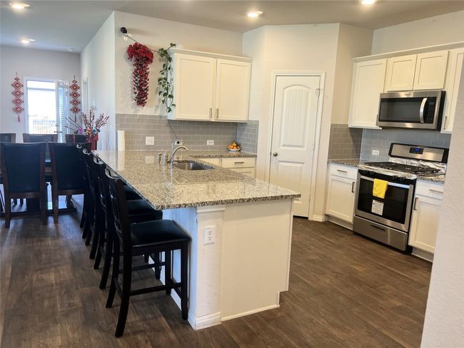 Kitchen featuring appliances with stainless steel finishes, a sink, a peninsula, white cabinets, and recessed lighting | Image 6