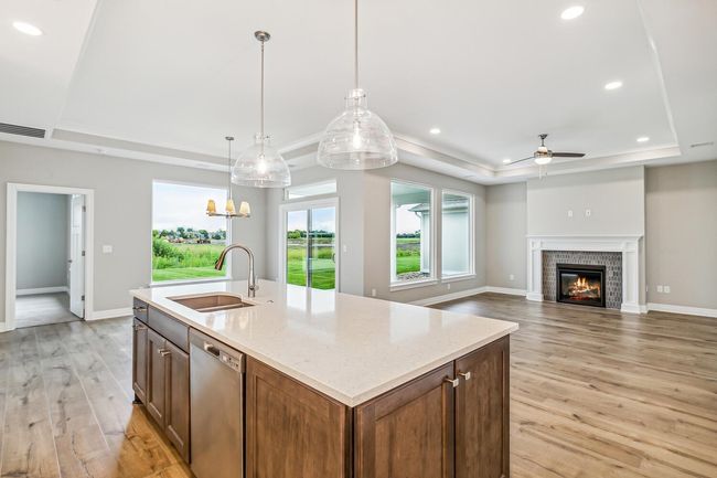 Kitchen featuring light wood-type flooring, dishwasher, a center island with sink, and a raised ceiling | Image 6