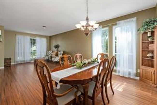 Dining room with a notable chandelier and wood finished floors | Image 13