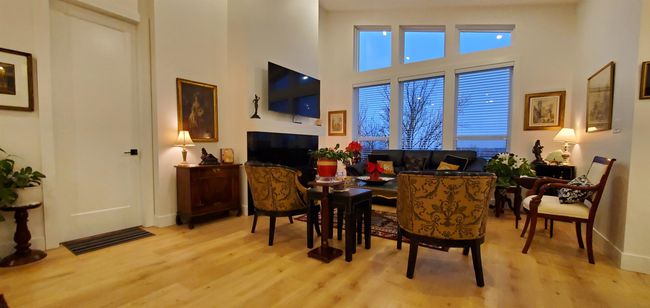 Living area with baseboards, visible vents, light wood finished floors, and a towering ceiling | Image 14