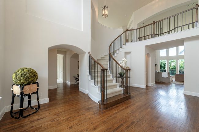 Foyer featuring arched walkways, a towering ceiling, stairway, and wood finished floors | Image 4