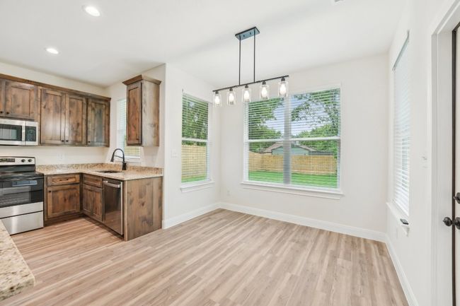 Kitchen featuring baseboards, appliances with stainless steel finishes, Vinyl Wood Plank floor, and a sink | Image 15