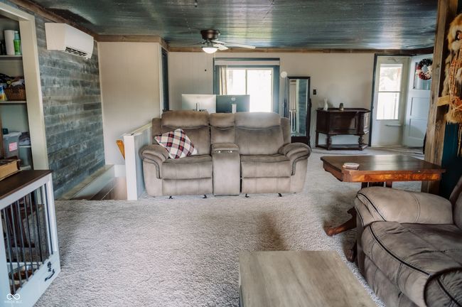 carpeted living area featuring a wall unit AC and a ceiling fan | Image 30