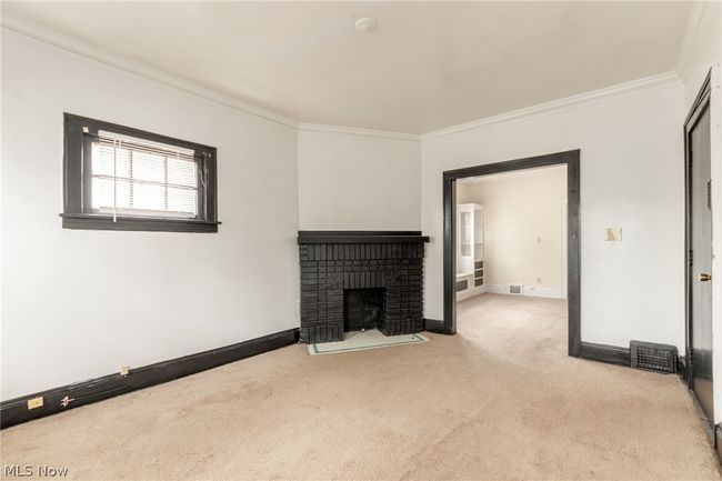 Unfurnished living room featuring ornamental molding, carpet flooring, and a brick fireplace | Image 4