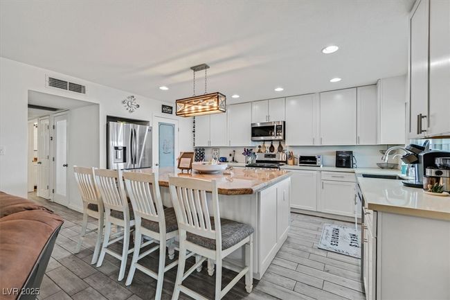 Kitchen with visible vents, a sink, stainless steel appliances, light countertops, and white cabinets | Image 4