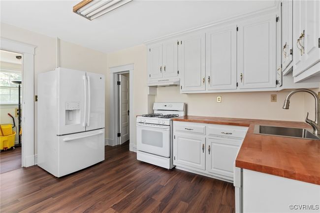 Kitchen featuring white appliances, countertops, a sink, under cabinet range hood, and hardwood flooring | Image 18