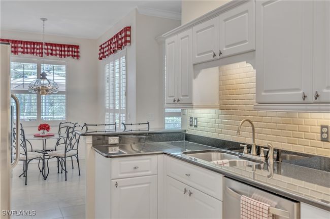 Kitchen with a sink, stainless steel dishwasher, white cabinetry, backsplash, and a peninsula | Image 10