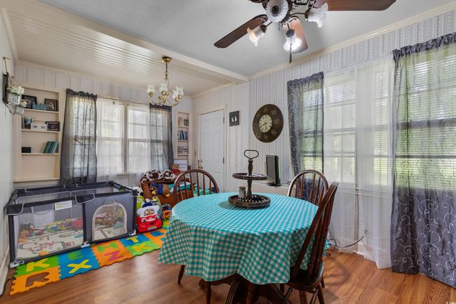 Dining space with a chandelier, wood finished floors, a ceiling fan, crown molding, and wallpapered walls | Image 14