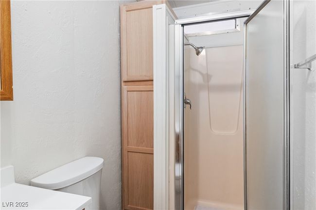 Bathroom with a textured wall, a shower stall, toilet, and vanity | Image 18