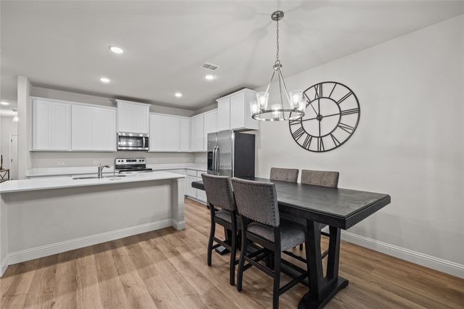 Kitchen with appliances with stainless steel finishes, light countertops, light wood finished floors, a chandelier, and recessed lighting | Image 12