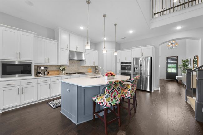 Kitchen featuring under cabinet range hood, appliances with stainless steel finishes, and white cabinetry | Image 8