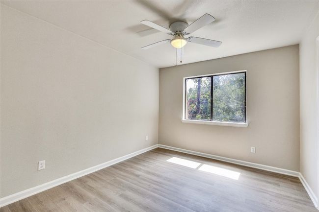 Spacious primary bedroom with updated flooring and ceiling fan. | Image 19