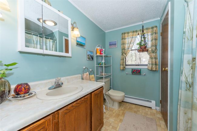 Full bathroom featuring a textured ceiling, a baseboard radiator, toilet, vanity, and crown molding | Image 18