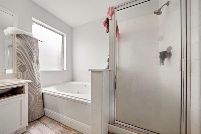 Enjoy everyday luxury in the ensuite bath, complete with a separate shower and oversized soaking tub—ideal for unwinding after a long day. A double-sink vanity with a large mirror enhances functionality, while the thoughtful layout ensures privacy and comfort within the suite. | Image 18