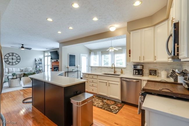 Kitchen with appliances with stainless steel finishes, a ceiling fan, open floor plan, decorative backsplash, and a textured ceiling | Image 4