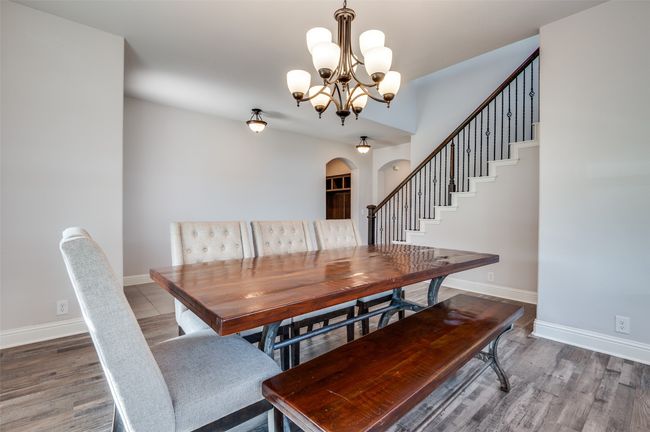Dining area featuring arched walkways, a chandelier, wood finished floors, and stairs | Image 4