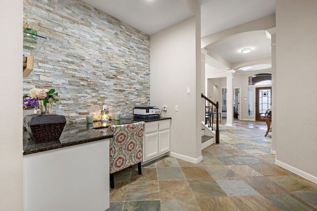 Hallway featuring arched walkways, stone tile flooring, decorative columns, and baseboards | Image 6
