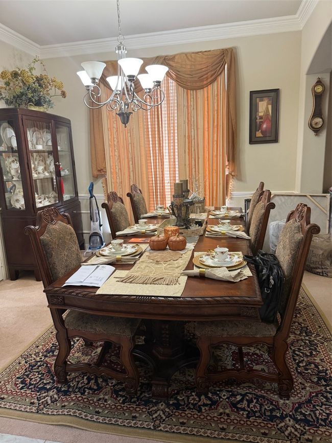 Carpeted dining space featuring ornamental molding and a chandelier | Image 6