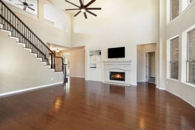 The spacious family room is the heart of the home, featuring soaring ceilings, a wall of windows that fills the space with natural light, and a cozy fireplace. | Image 17