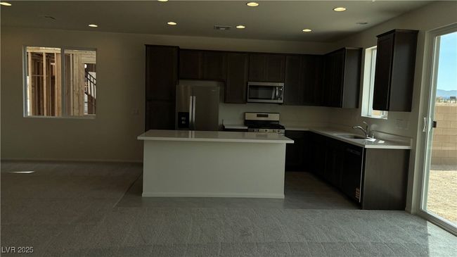 Kitchen featuring a sink, stainless steel appliances, light countertops, recessed lighting, and light carpet | Image 11