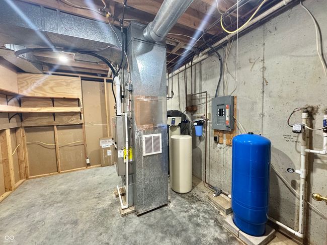 unfinished below grade area featuring a water pressure tank, electric panel, and a water softener system | Image 67