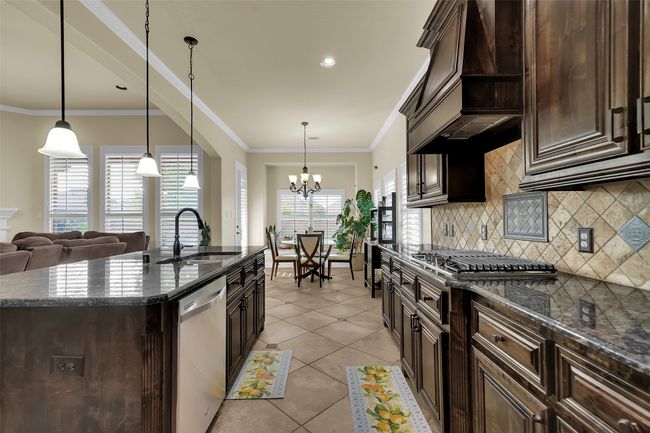 Kitchen featuring dark brown cabinets, ornamental molding, decorative light fixtures, appliances with stainless steel finishes, and recessed lighting | Image 7