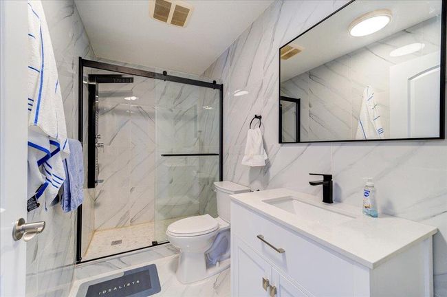 Full bathroom featuring toilet, vanity, tile walls, a marble finish shower, and marble finish floors | Image 34