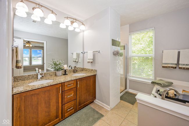 Updated primary bathroom with tiled shower, garden tub, & dual vanity with granite countertop. | Image 33