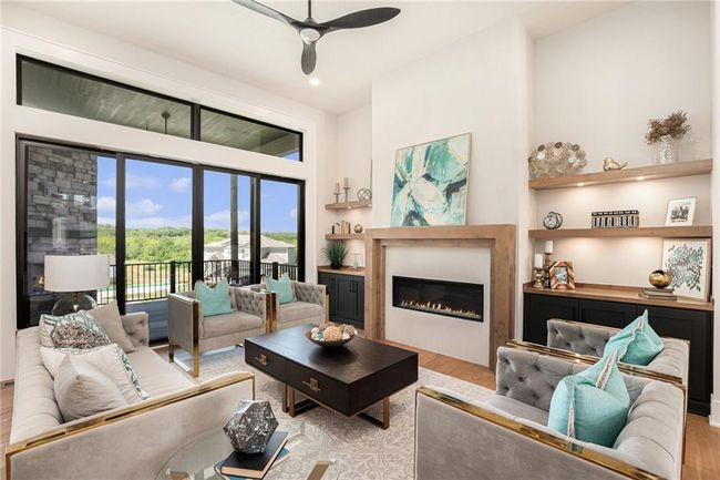 Living area with wood finished floors, ceiling fan, a glass covered fireplace, and recessed lighting | Image 4