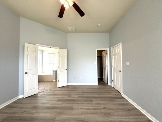 Unfurnished bedroom featuring wood finished floors, ensuite bath, a ceiling fan, and a closet | Image 9