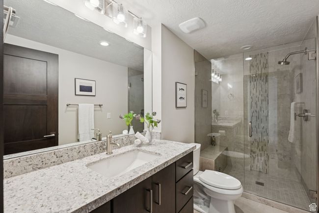 Full bathroom featuring vanity, a stall shower, and a textured ceiling | Image 49