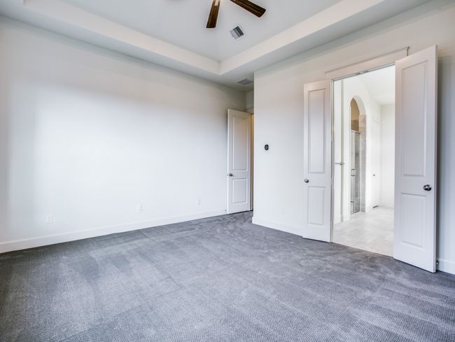 Unfurnished bedroom with carpet, arched walkways, ceiling fan, and a tray ceiling | Image 14