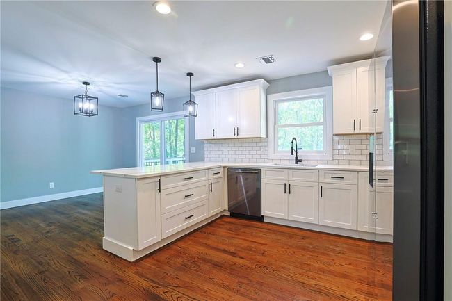 Kitchen featuring sink, dishwashing machine, dark hardwood / wood-style floors, stainless steel fridge, and kitchen peninsula | Image 4