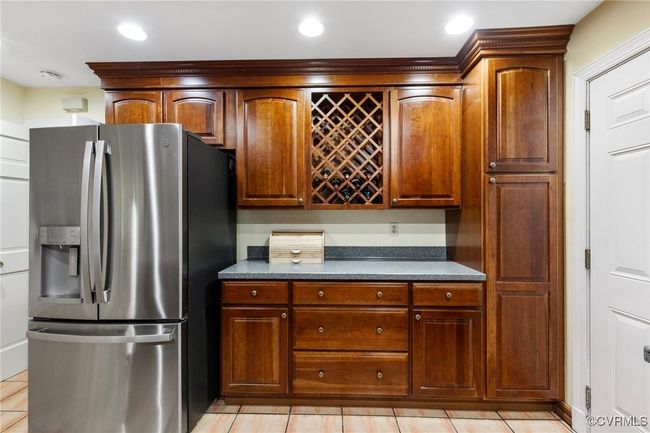 Kitchen with stainless steel fridge with ice dispenser, dark countertops, light tile patterned floors, and recessed lighting | Image 13