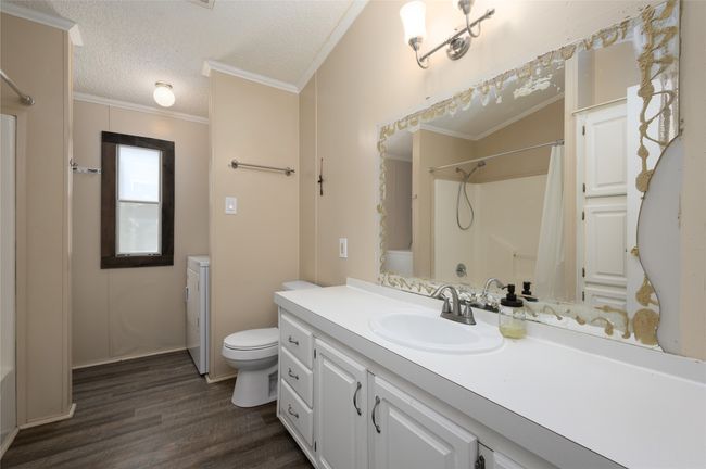 Bathroom with toilet, wood finished floors, a textured ceiling, a shower with curtain, and vanity | Image 20