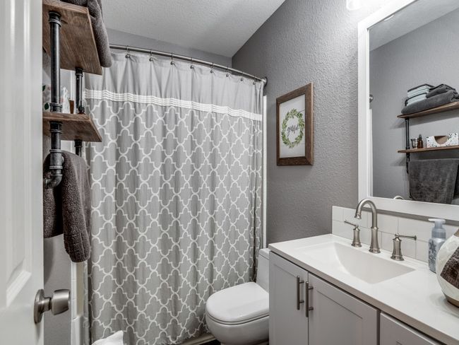 Bathroom featuring a textured wall, toilet, vanity, a shower with curtain, and a textured ceiling | Image 22