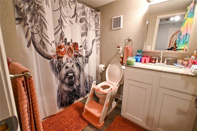Bathroom with a textured wall, vanity, toilet, a shower with shower curtain, and a textured ceiling | Image 25