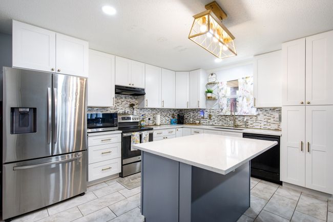 Kitchen with appliances with stainless steel finishes, under cabinet range hood, backsplash, light tile patterned floors, and recessed lighting | Image 6