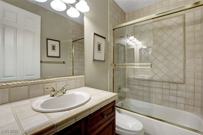 Full bathroom featuring combined bath / shower with glass door, vanity, and toilet | Image 42