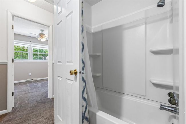 Bathroom with shower / bathtub combination with curtain, a ceiling fan, baseboards, and a textured ceiling | Image 54