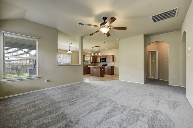 Unfurnished living room featuring arched walkways, light carpet, and a ceiling fan | Image 9