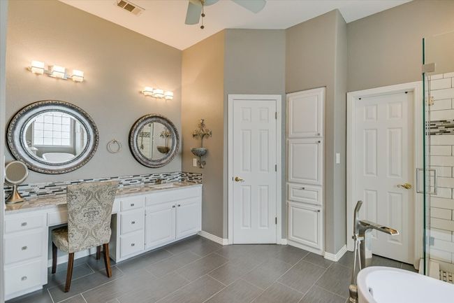 Full bath featuring ceiling fan, vanity, decorative backsplash, a tub to relax in, and baseboards | Image 16