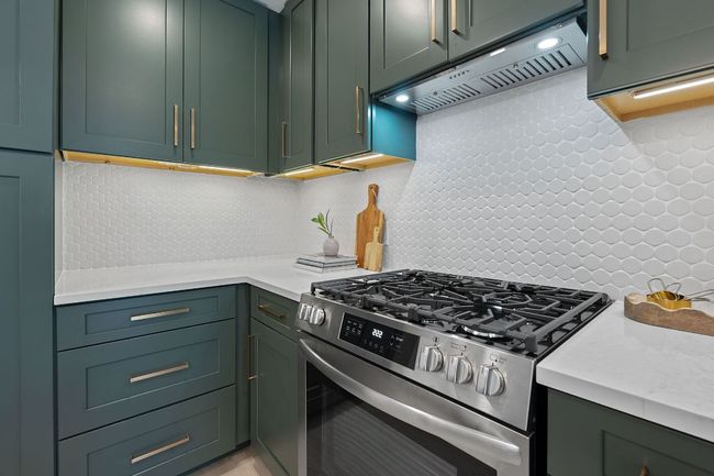 Kitchen featuring gas stove, extractor fan, light countertops, and decorative backsplash | Image 10