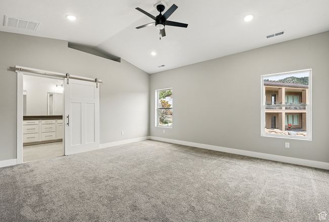 Spare room with a barn door, light carpet, a ceiling fan, lofted ceiling, and baseboards | Image 25